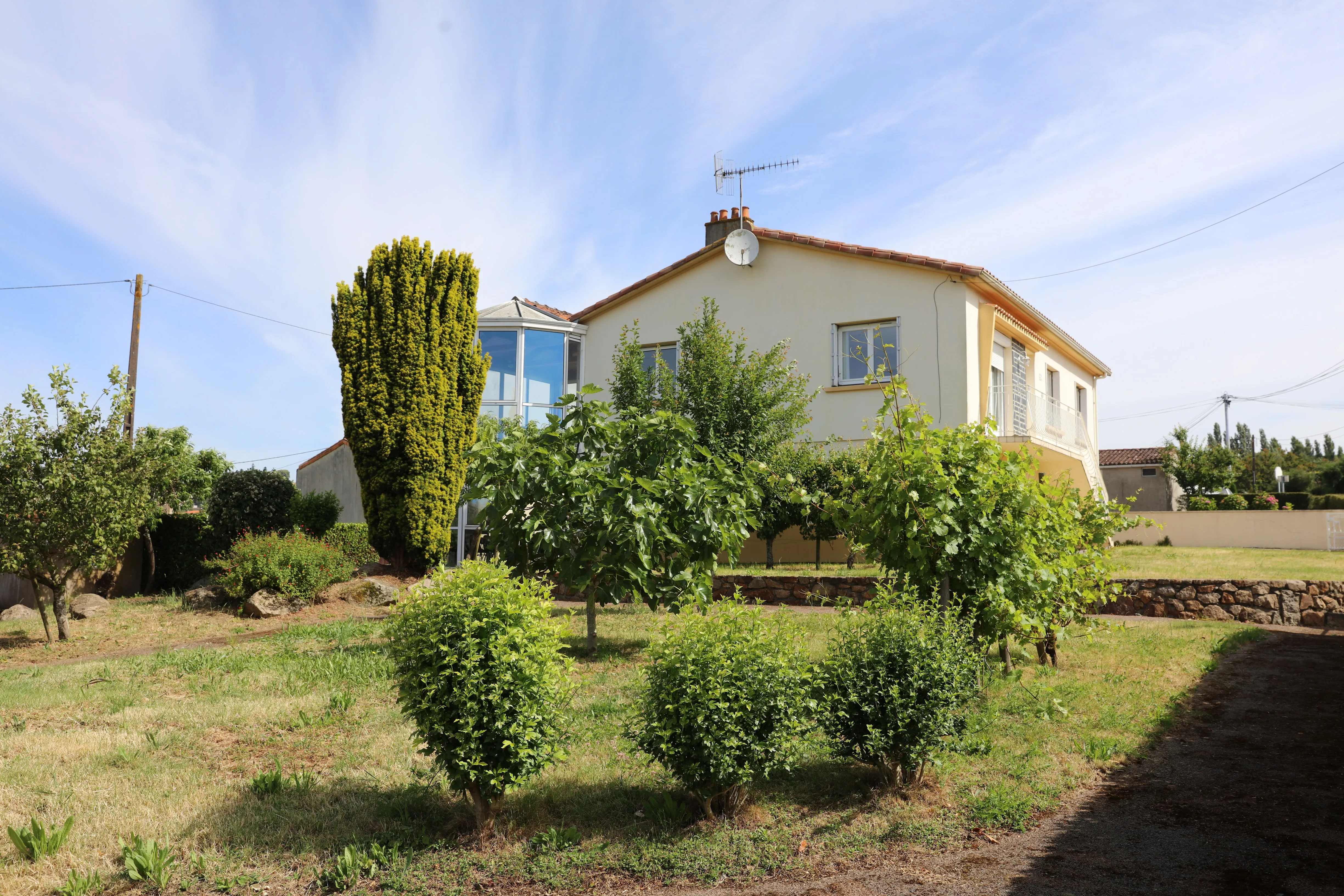 Façade du gîte de Mellonia à Pouzauges, maison avec véranda et jardin arboré