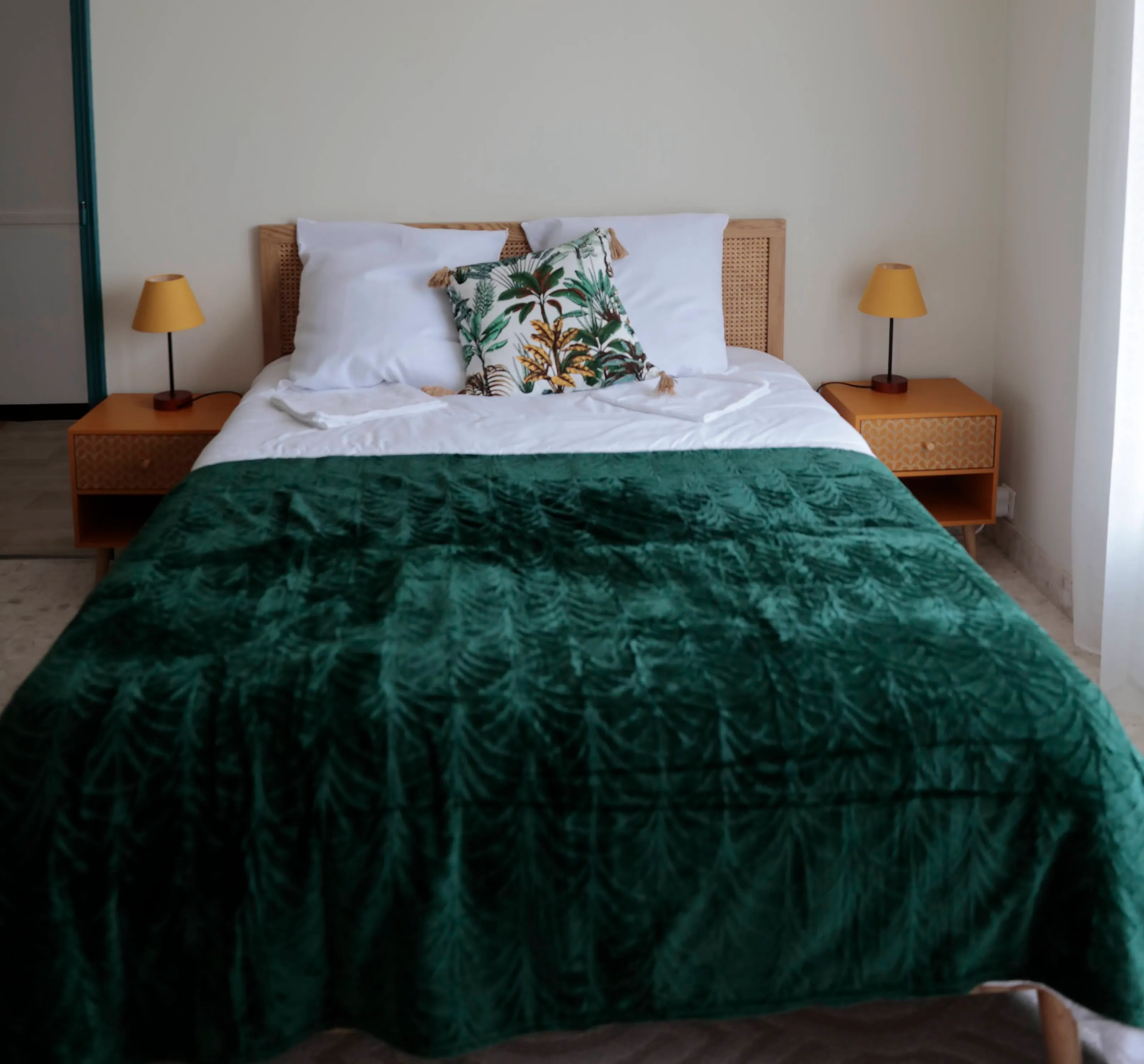 Chambre Céladon du gîte de Mellonia à Pouzauges : lit double à tête de lit cannée, jeté en velours vert et chevets en rotin
