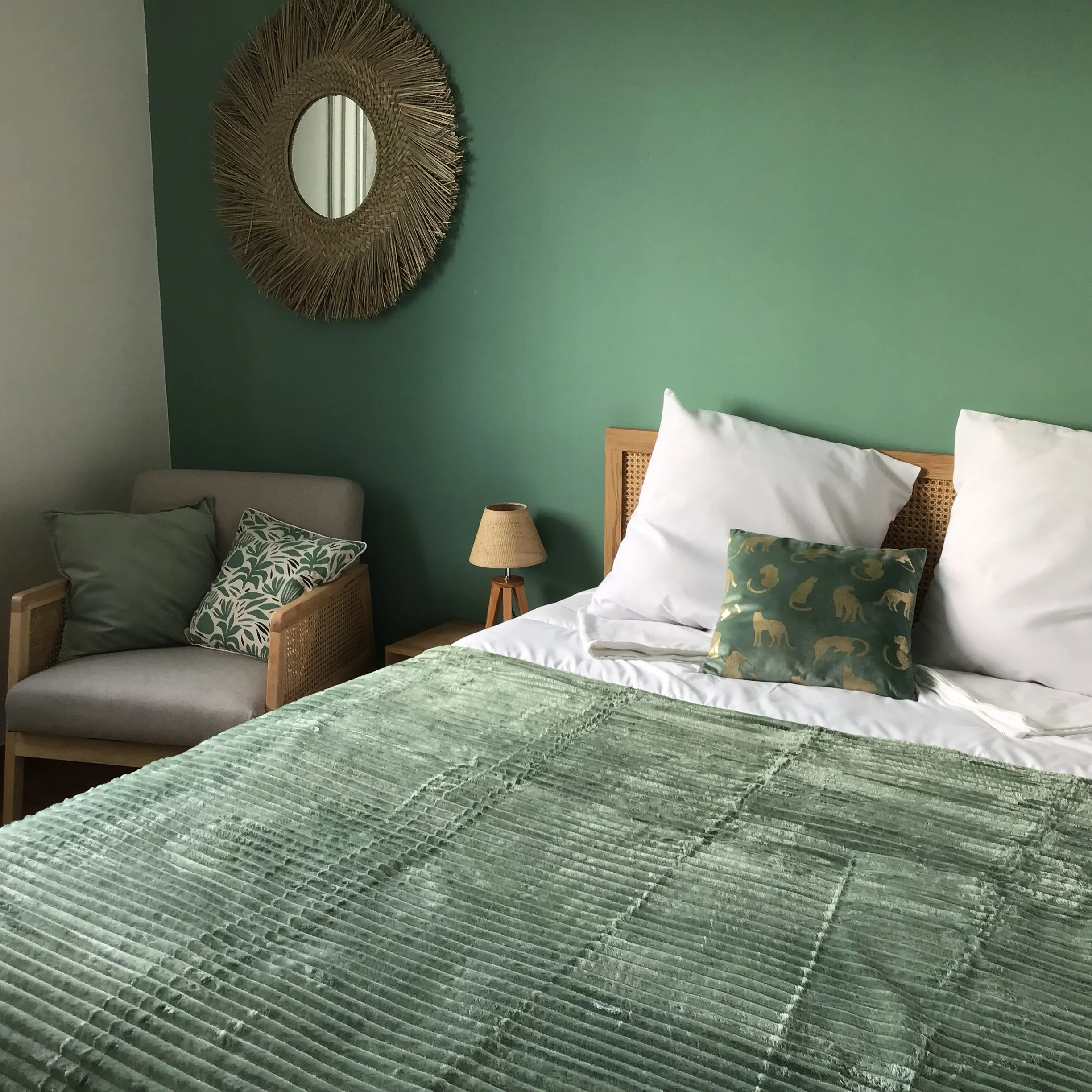 Chambre Vert sauge du gîte de Mellonia : mur vert, miroir soleil, fauteuil cannée et lit double