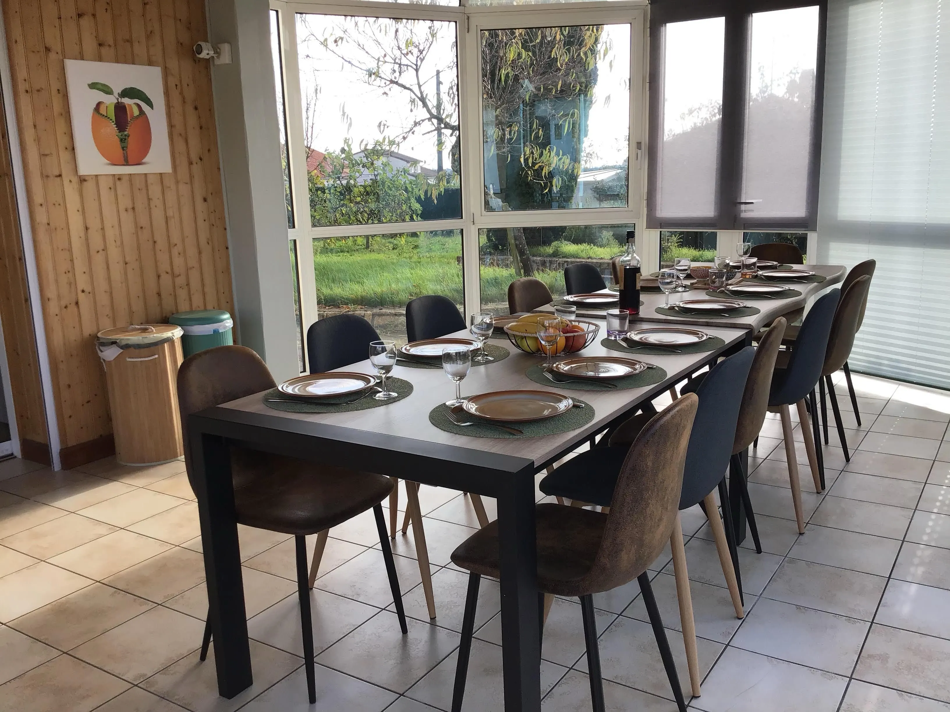 Véranda salle à manger du gîte de Mellonia : grande tablée dressée pour le groupe, avec vue sur le jardin